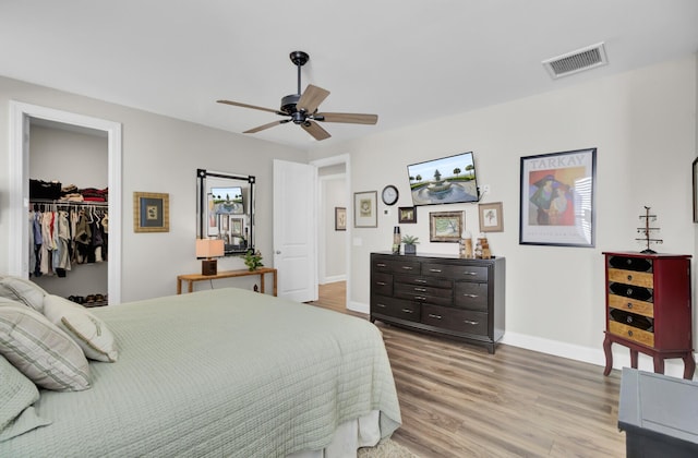 bedroom with ceiling fan, a spacious closet, a closet, and light wood-type flooring