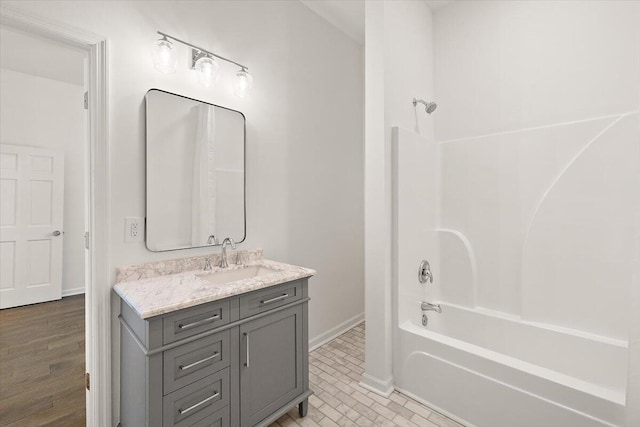 bathroom with baseboards, shower / bathing tub combination, and vanity