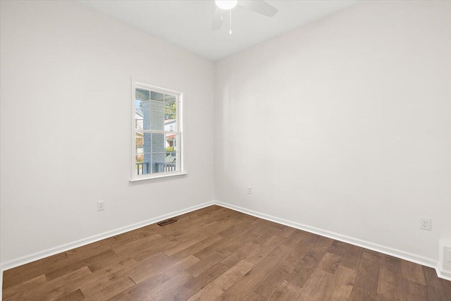 empty room with a ceiling fan, baseboards, dark wood finished floors, and visible vents