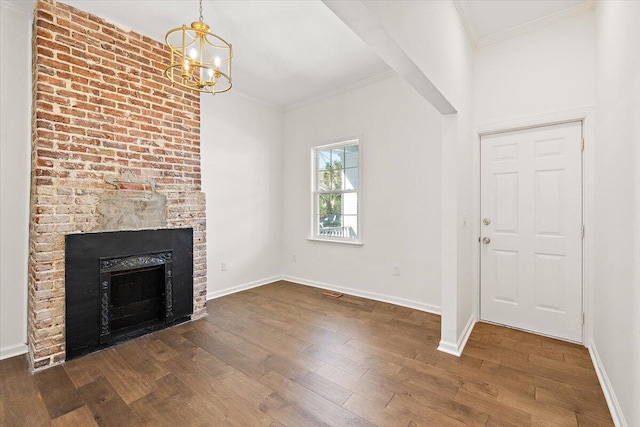 unfurnished living room with crown molding, dark wood-style flooring, an inviting chandelier, a brick fireplace, and baseboards