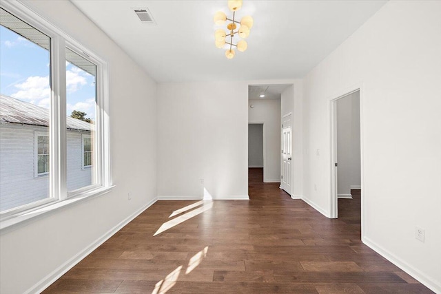 unfurnished room featuring visible vents, baseboards, wood finished floors, and an inviting chandelier
