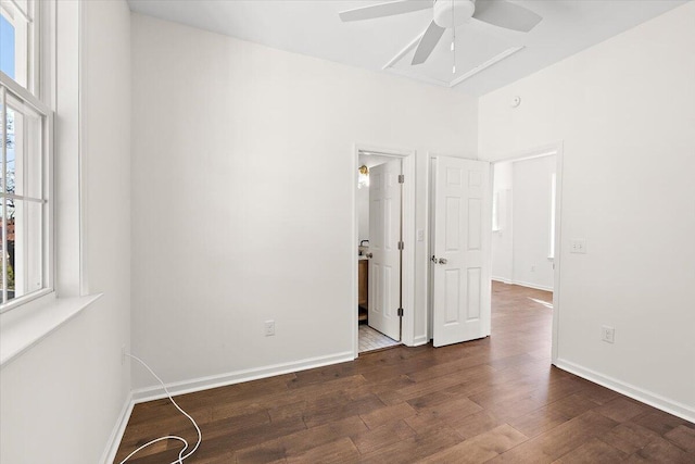 unfurnished bedroom featuring baseboards, multiple windows, and dark wood-type flooring