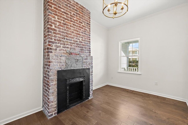 unfurnished living room with a notable chandelier, dark wood finished floors, ornamental molding, and a fireplace