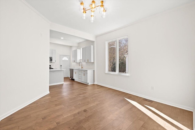 unfurnished living room with baseboards, wood finished floors, a notable chandelier, and a wealth of natural light