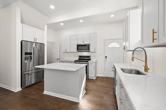 kitchen with a sink, light stone counters, stainless steel appliances, and dark wood-style flooring