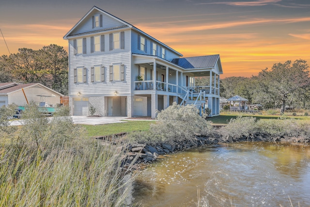 back house at dusk with covered porch and a water view