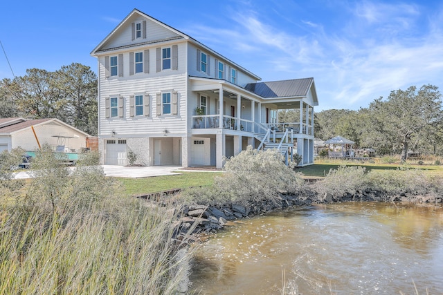 rear view of house featuring a water view, a porch, and a garage