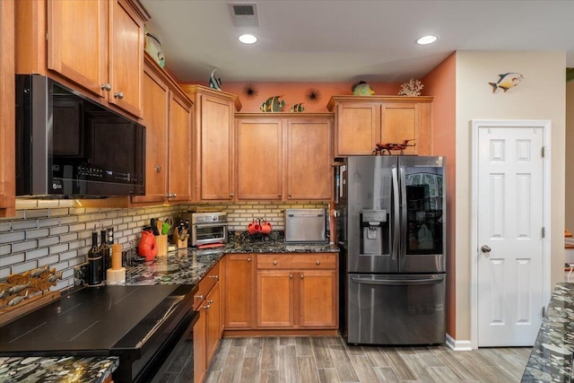 kitchen with tasteful backsplash, black range oven, stainless steel fridge with ice dispenser, dark stone counters, and light wood-type flooring