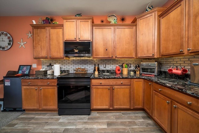 kitchen with wood-type flooring, backsplash, dark stone counters, and black / electric stove