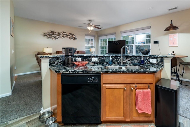 kitchen featuring sink, dishwasher, ceiling fan, dark stone countertops, and carpet floors