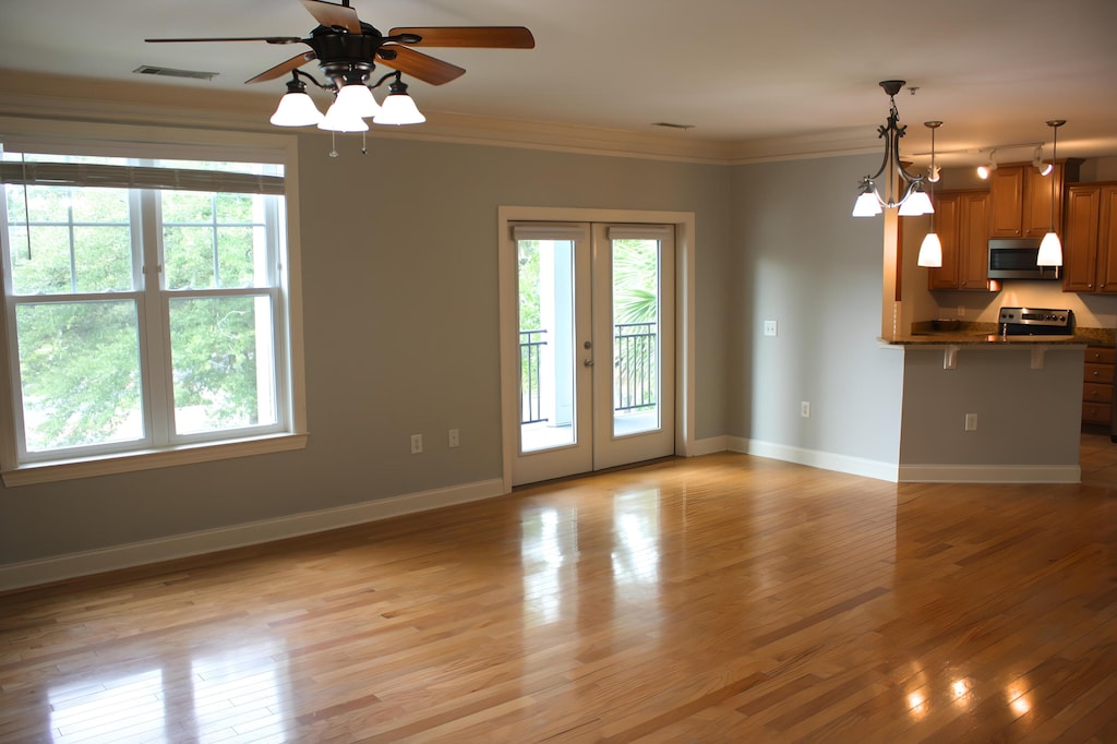 empty room featuring crown molding, ceiling fan, light wood-type flooring, and french doors