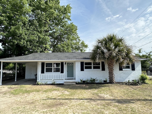 single story home featuring brick siding, an attached carport, covered porch, and a front yard