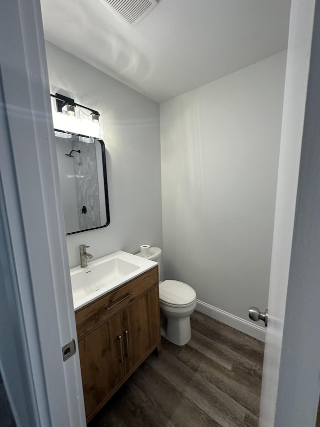 bathroom with wood finished floors, toilet, and vanity