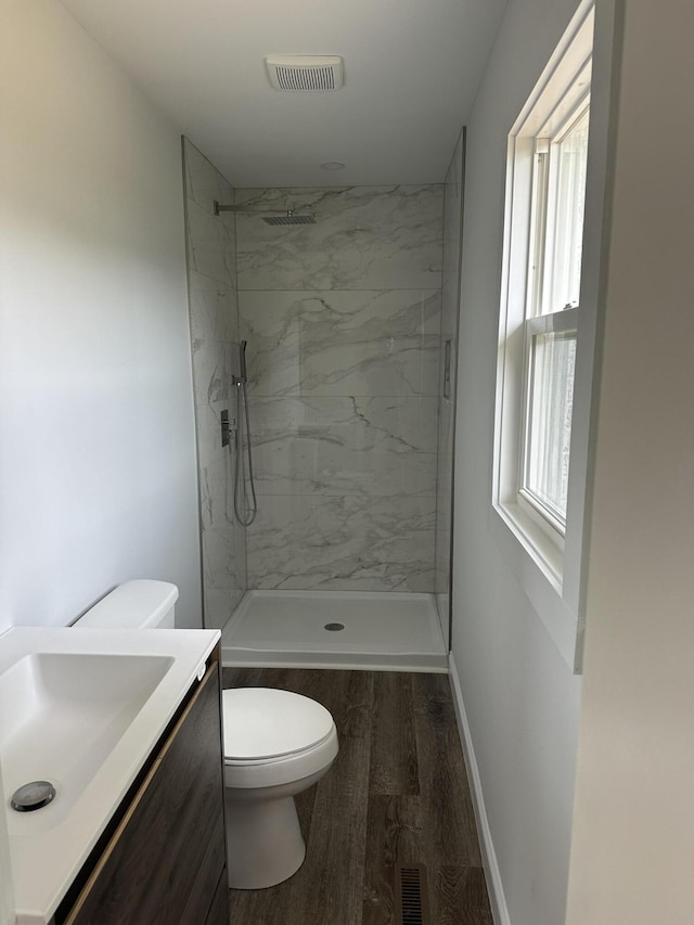 full bath featuring toilet, wood finished floors, and a marble finish shower