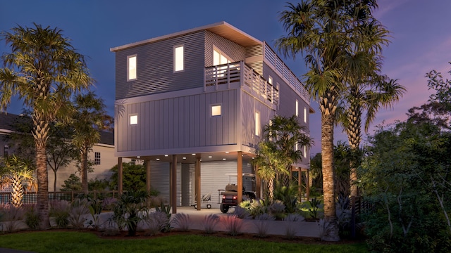 back of house with board and batten siding, a balcony, and a patio area