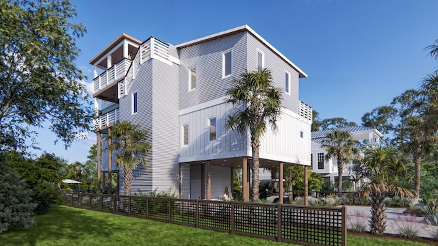 rear view of property featuring a balcony, a lawn, and fence