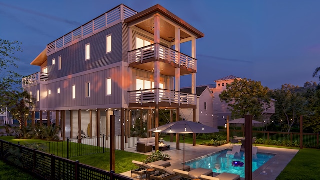 back of property featuring a balcony, a fenced backyard, outdoor lounge area, a lawn, and a patio area