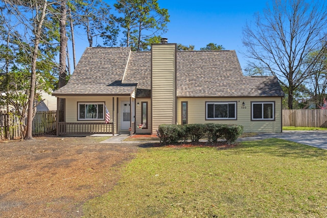 view of front of house with a front lawn, fence, roof with shingles, covered porch, and a chimney