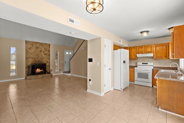 kitchen with visible vents, a sink, open floor plan, white appliances, and a stone fireplace