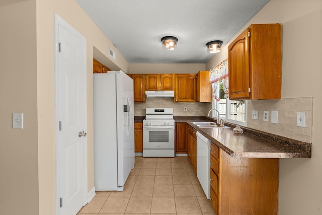 kitchen featuring white appliances, visible vents, a sink, under cabinet range hood, and dark countertops