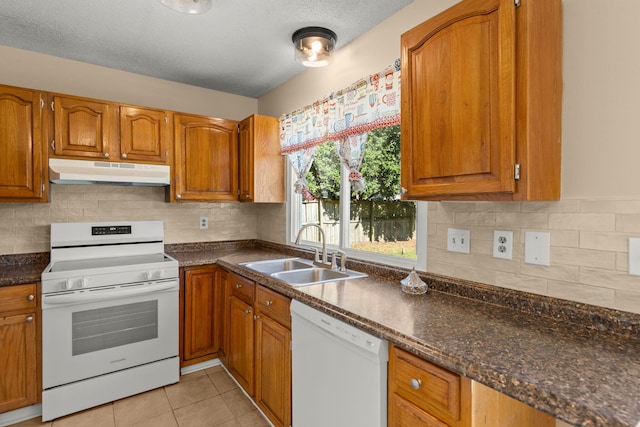 kitchen featuring under cabinet range hood, white appliances, brown cabinetry, and a sink