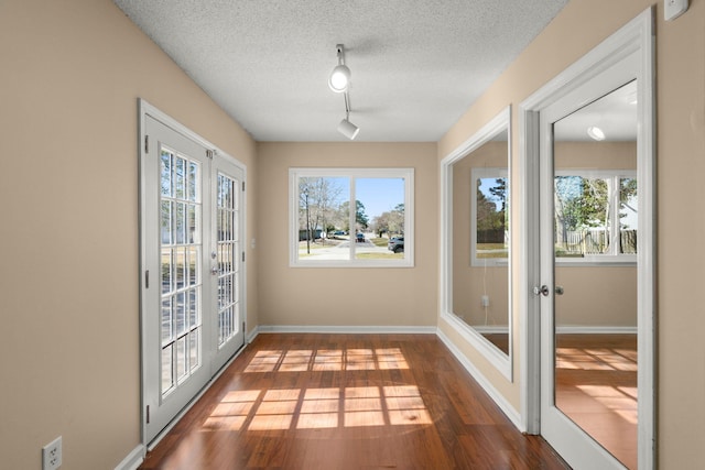 unfurnished sunroom with rail lighting, plenty of natural light, and french doors