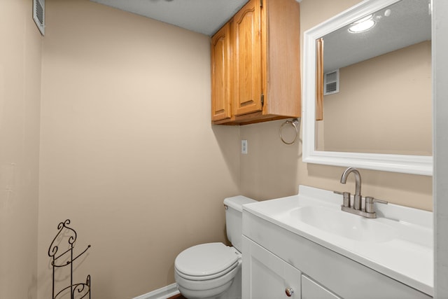 bathroom featuring visible vents, baseboards, toilet, and vanity