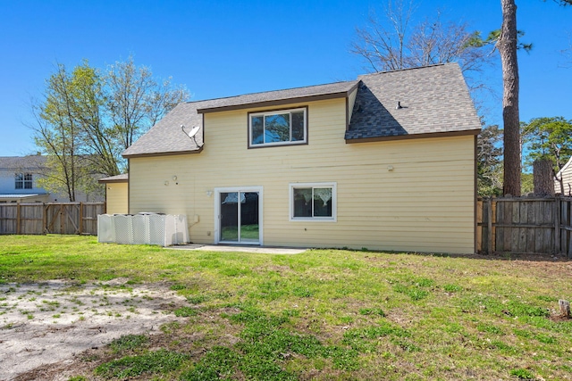 back of house featuring a lawn, roof with shingles, and a fenced backyard