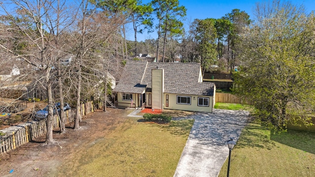 view of front of home with a front lawn, fence, and a shingled roof