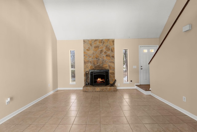 unfurnished living room with light tile patterned floors, baseboards, lofted ceiling, and a stone fireplace