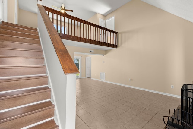 stairs featuring a ceiling fan, baseboards, visible vents, high vaulted ceiling, and tile patterned floors