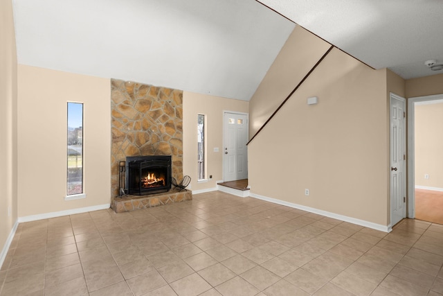 unfurnished living room with light tile patterned floors, lofted ceiling, a healthy amount of sunlight, and a fireplace