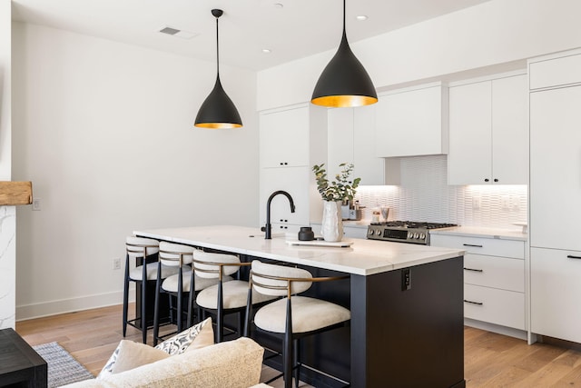 kitchen featuring light wood-style flooring, stainless steel range with gas stovetop, modern cabinets, and visible vents