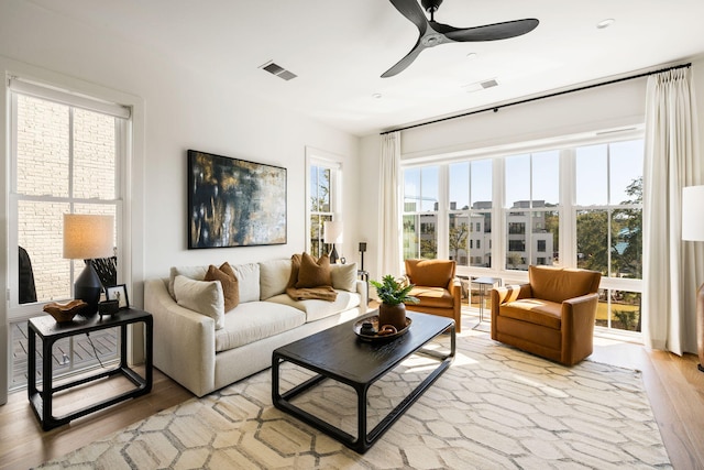 living area featuring visible vents, light wood-type flooring, and a ceiling fan