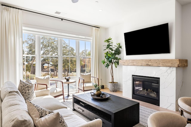 living room featuring a premium fireplace, wood finished floors, and recessed lighting