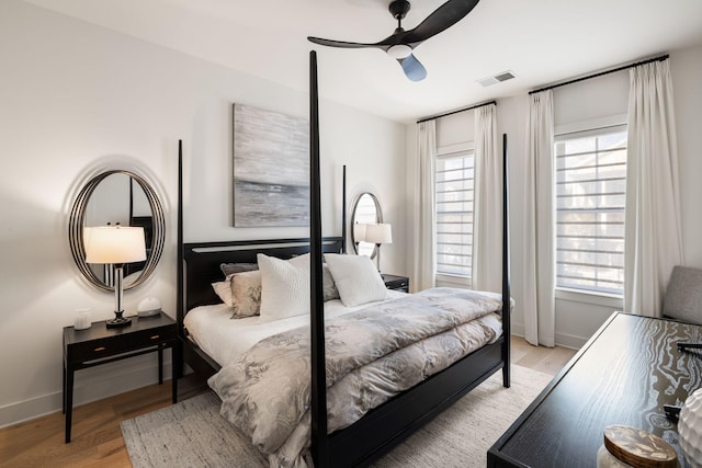 bedroom featuring visible vents, baseboards, ceiling fan, and wood finished floors