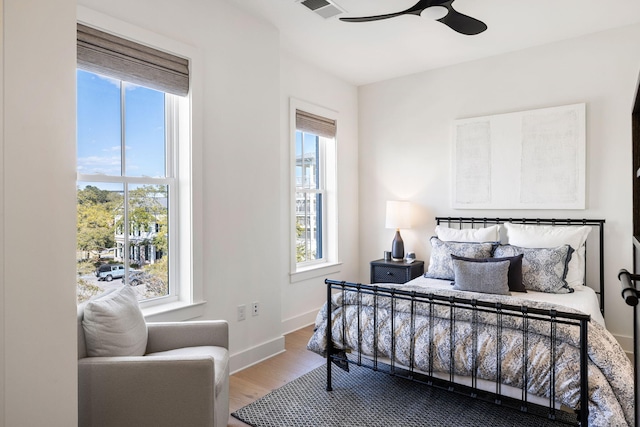 bedroom with wood finished floors, baseboards, multiple windows, and visible vents