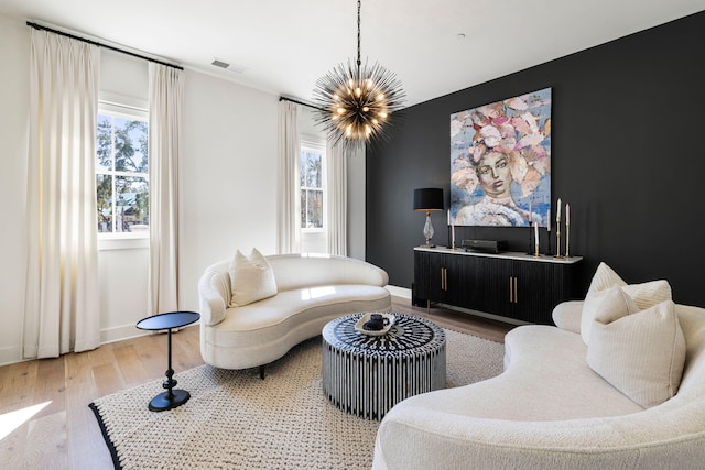 living room featuring visible vents, a wealth of natural light, an inviting chandelier, and wood finished floors