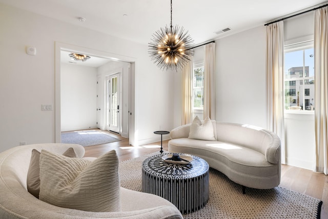 living room featuring a chandelier, visible vents, and wood finished floors