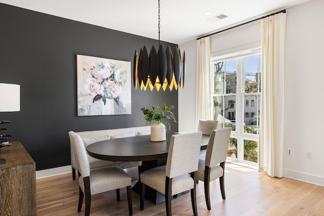 dining room featuring light wood-style flooring, a healthy amount of sunlight, baseboards, and visible vents