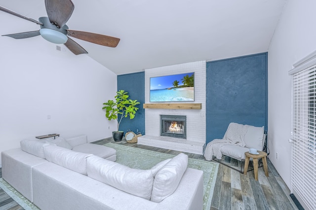 living room featuring wood-type flooring, a fireplace, vaulted ceiling, and ceiling fan