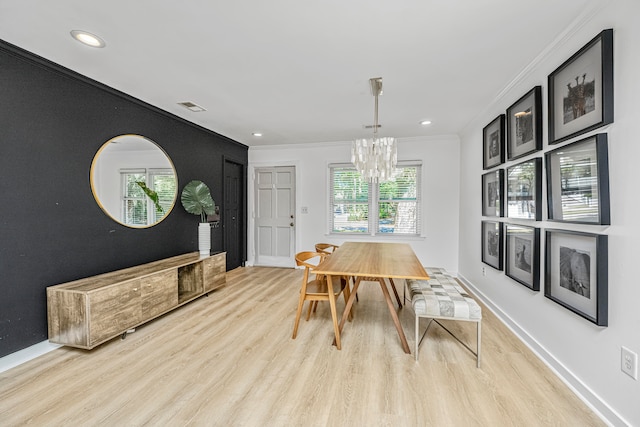 dining space with ornamental molding, a chandelier, and light hardwood / wood-style floors