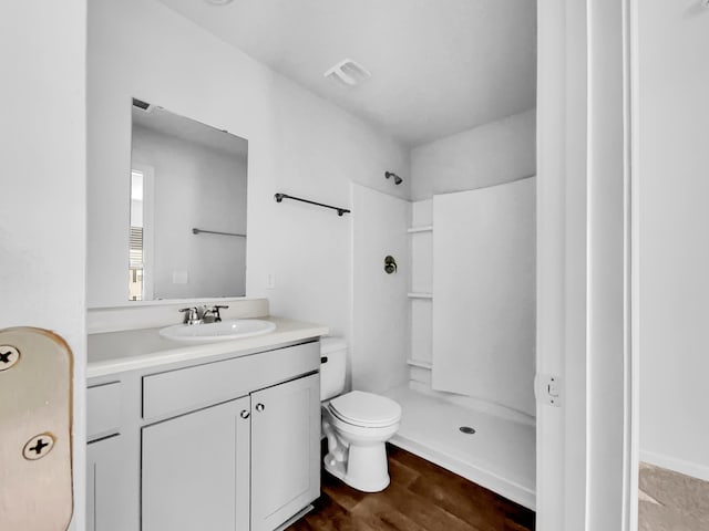 bathroom featuring toilet, hardwood / wood-style flooring, vanity, and walk in shower