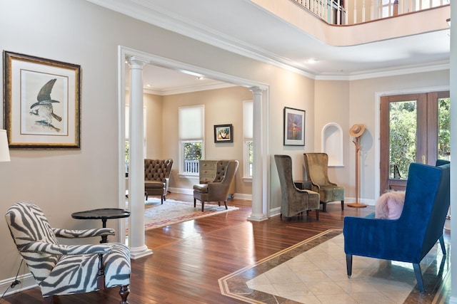 living area featuring crown molding, wood-type flooring, and ornate columns