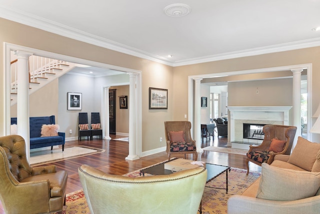 living room featuring ornate columns, a tiled fireplace, ornamental molding, and hardwood / wood-style flooring