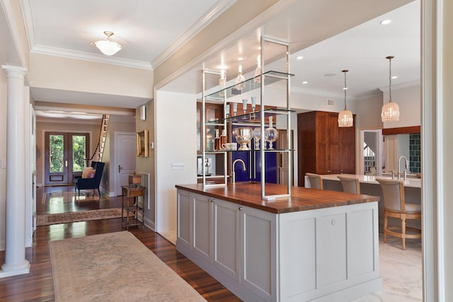 kitchen featuring a center island with sink, decorative columns, dark wood-type flooring, and french doors