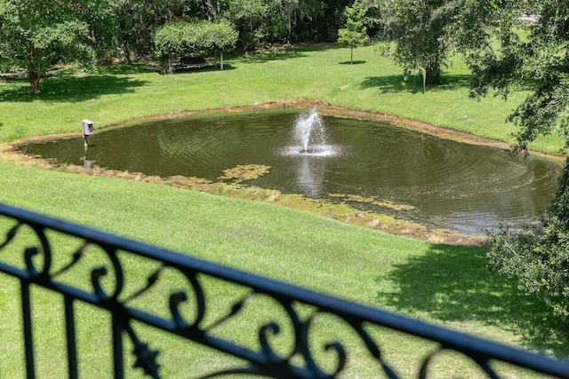 surrounding community with a water view and a lawn