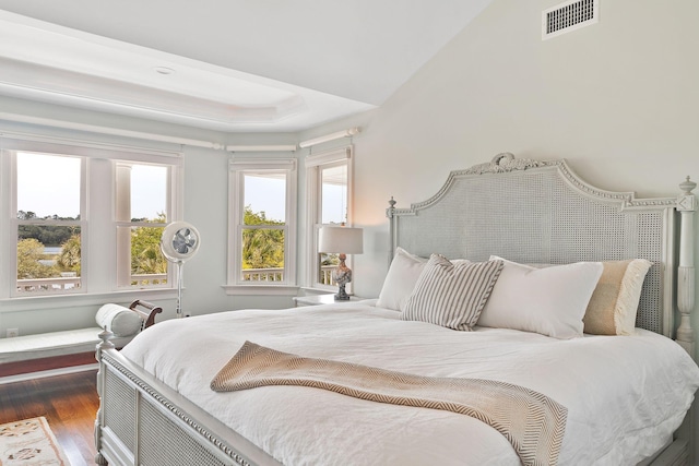 bedroom with a raised ceiling and dark wood-type flooring