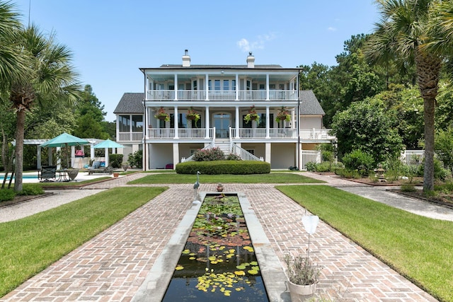 back of property with a balcony and a yard