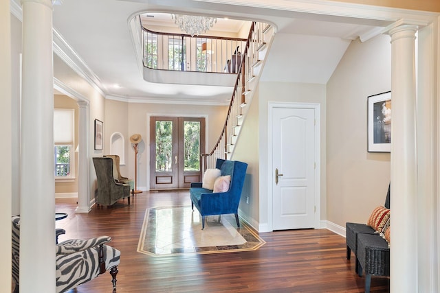 foyer entrance featuring decorative columns, a chandelier, crown molding, french doors, and dark hardwood / wood-style flooring